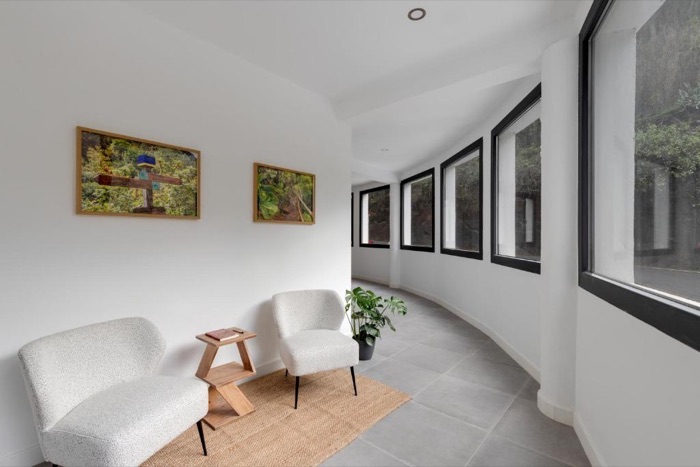 Galería blanca con butacas junto a los ventanales