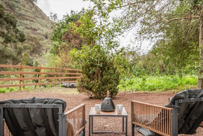 Terraza de madera con butacas, abierta al bosque